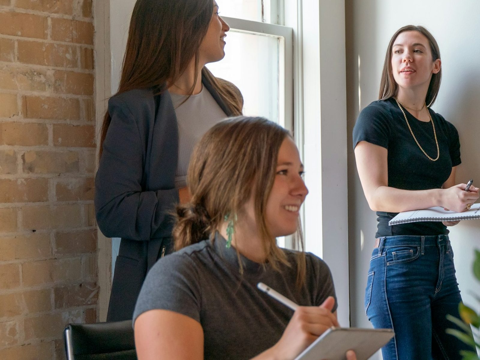 Three colleagues talking a piece of work through together in a bright office